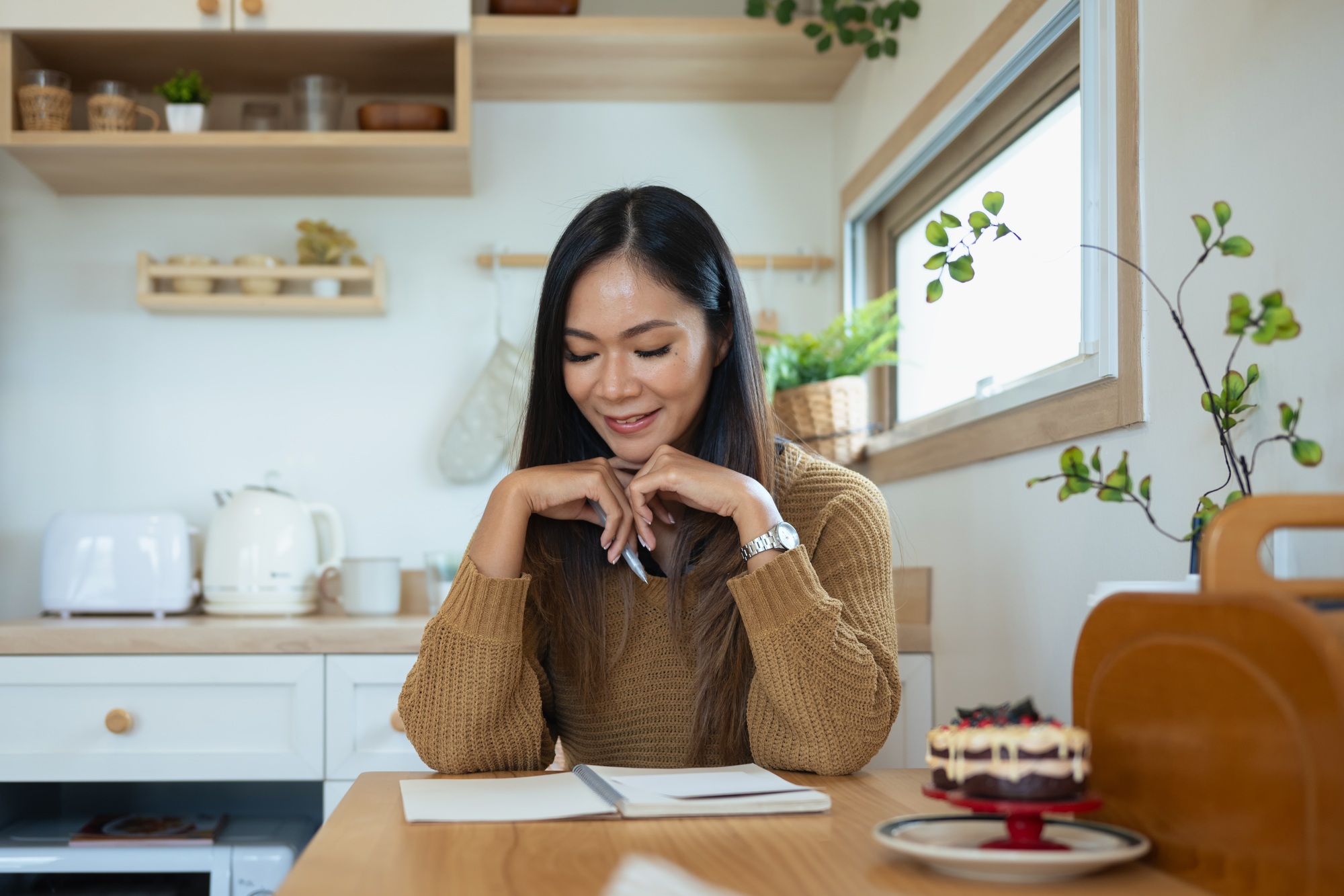 Young adult woman journaling in the kitchen