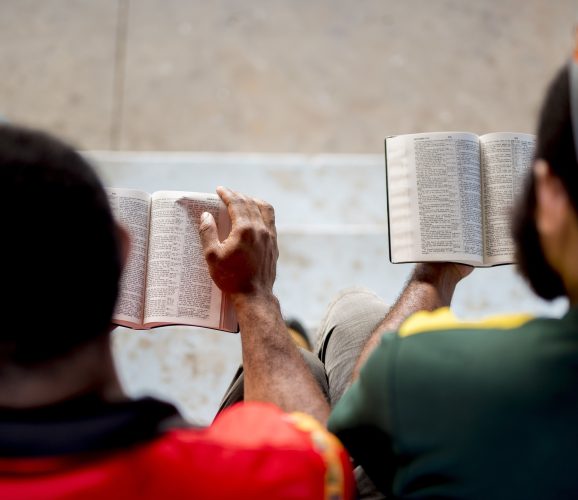 Overhead shot of people sitting and reading the bible with a blurred background